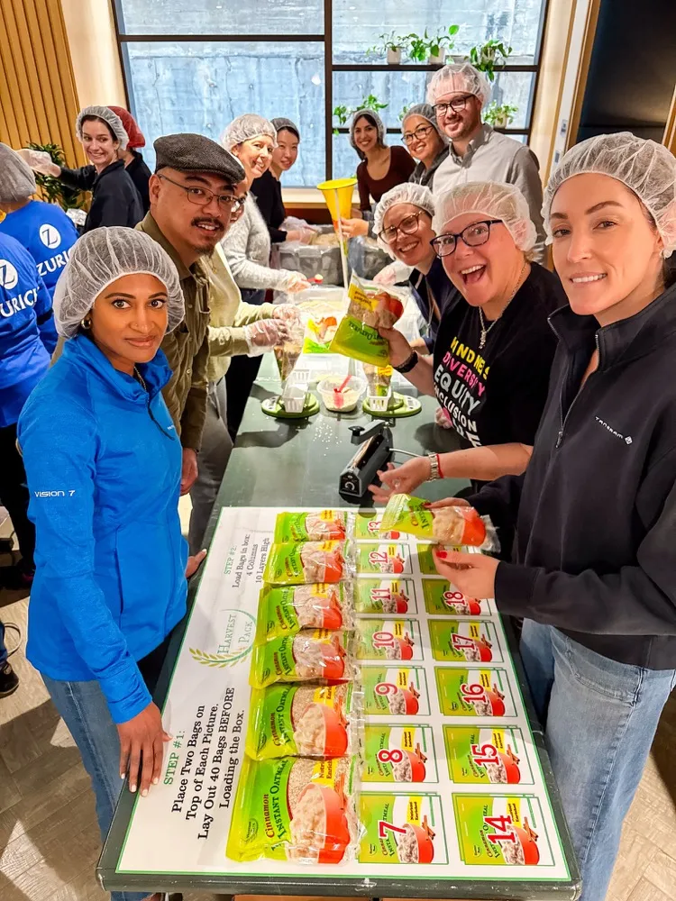 Coworkers packing meals together at a business Harvest Pack event