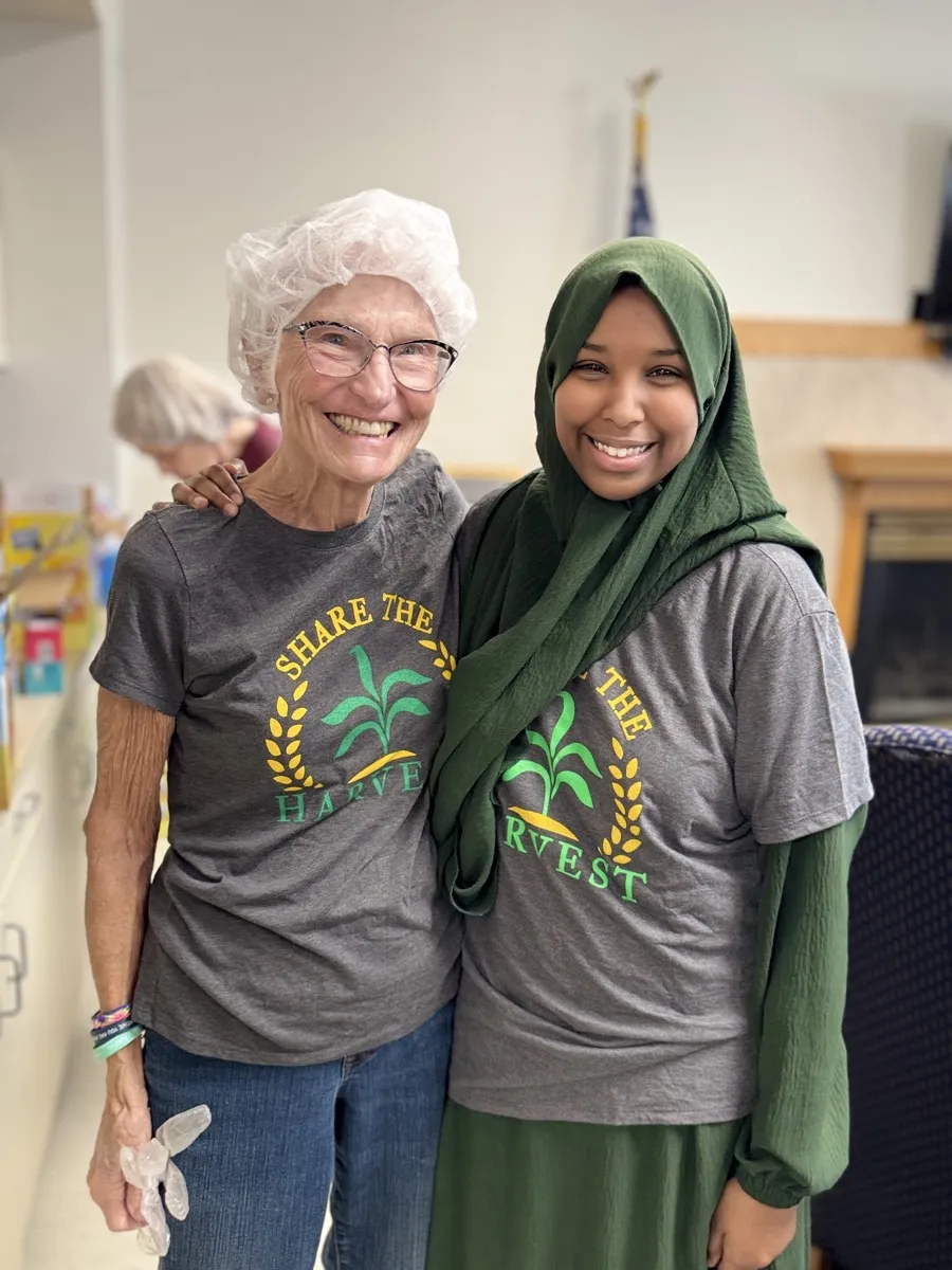 Rows of volunteers at packing tables during a Harvest Pack event