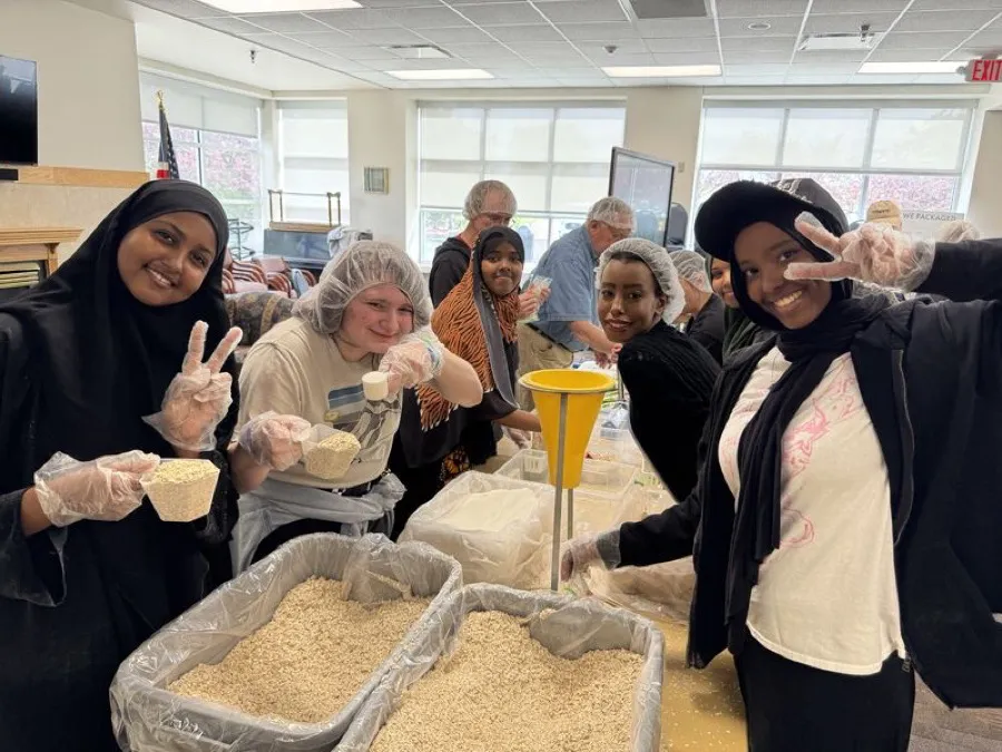 Young volunteers flashing peace signs over trays of oats